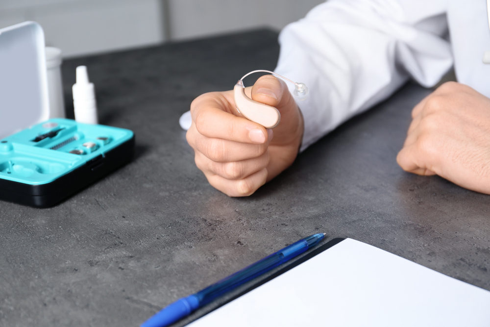 Doctor,holding,hearing,aid,at,table,,closeup.,medical,objects