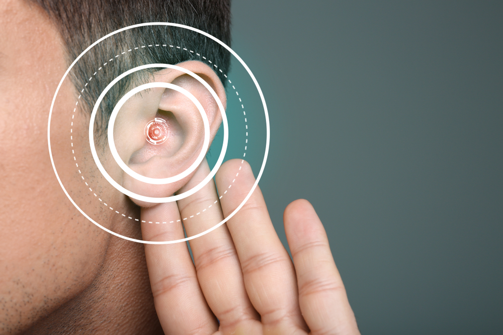 Young,man,with,symptom,of,hearing,loss,on,color,background